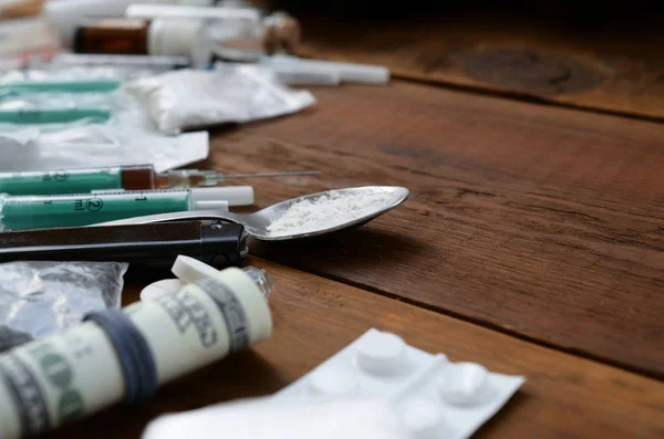 Багато наркотичних речовин і пристроїв для приготування ліків лежать на старому дерев'яному столі — стокове фото