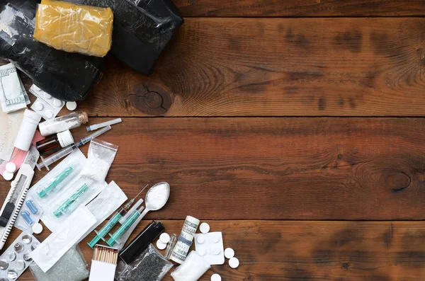 Una gran cantidad de sustancias narcóticas y dispositivos para la preparación de drogas se encuentran en una vieja mesa de madera — Foto de Stock