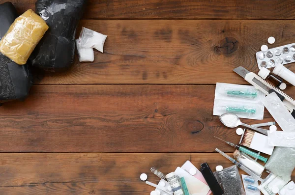 Una gran cantidad de píldoras narcóticas y dispositivos para la preparación de drogas se encuentran en una vieja mesa de madera — Foto de Stock