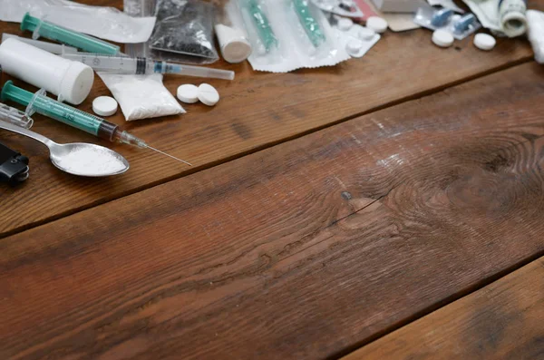 A lot of narcotic substances and devices for the preparation of drugs lie on an old wooden table — Stock Photo, Image