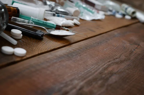 Auf einem alten Holztisch liegen viele Betäubungsmittel und Geräte zur Zubereitung von Drogen — Stockfoto