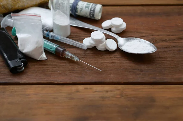 Wiele substancji odurzających i urządzeń do przygotowywania narkotyków leży na starym drewnianym stole. — Zdjęcie stockowe