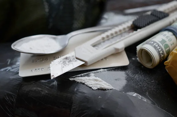 Colher cheia de heroína e faca de papel está em pacotes de drogas e cartão de crédito com rolo de dólares — Fotografia de Stock