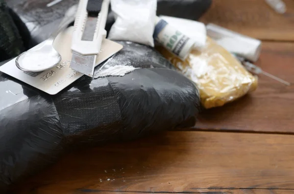 Cuchara llena de heroína y cuchillo de papel se encuentra en paquetes de drogas y tarjeta de crédito con rollo de dólares — Foto de Stock