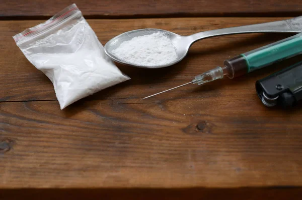 Zapalniczka strzykawki i łyżka pełna białego proszku na drewnianym tle. Koncepcja uzależnienia od heroiny — Zdjęcie stockowe