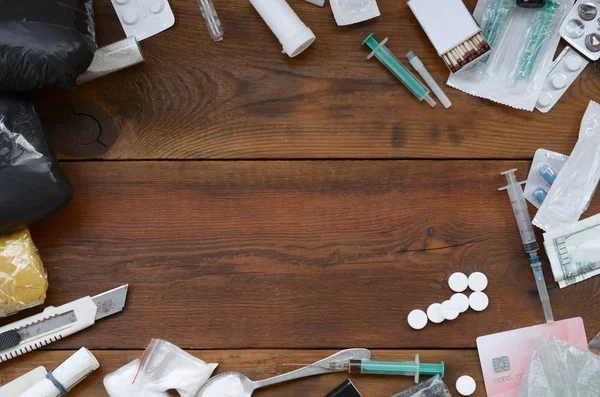 A lot of narcotic substances and devices for the preparation of drugs lie on an old wooden table — Stock Photo, Image