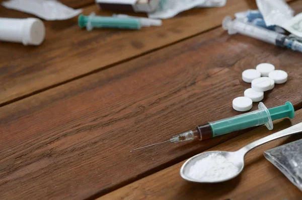 Mnoho omamných látek a zařízení pro přípravu drog leží na starém dřevěném stole — Stock fotografie