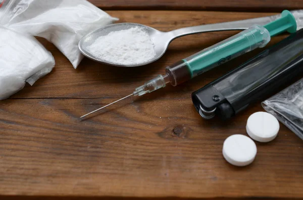 Wiele substancji odurzających i urządzeń do przygotowywania narkotyków leży na starym drewnianym stole. — Zdjęcie stockowe