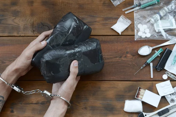 Drug trafficker arrested with their heroin packages. Police arrest drug dealer with handcuffs and many narcotic stuff on wooden table — Stock Photo, Image