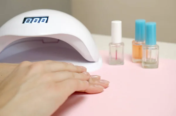 Close up female hands with beautiful trendy transparent manicure on white table background