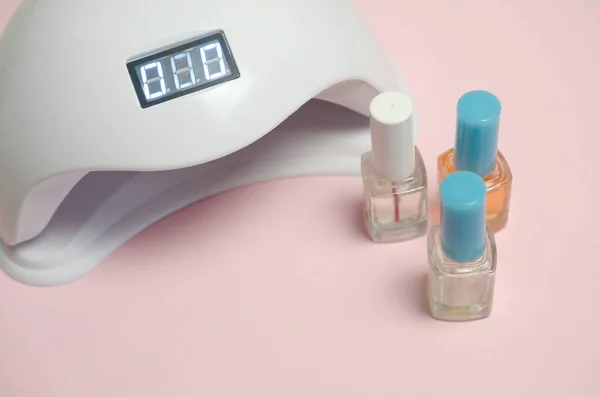 UV-Diodenlampe für Nägel und Kosmetik-Nagellack für Maniküre und Pediküre auf pastellfarbenem Hintergrund — Stockfoto