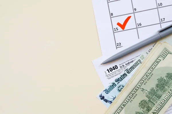 1040 individuelle Einkommensteuererklärung mit Rückerstattungsscheck und Hundert-Dollar-Scheinen auf Kalender mit Markierung am 15. April — Stockfoto