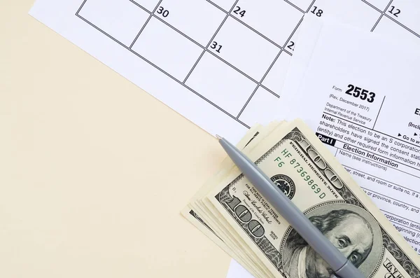 Formulário de IRS 2553 Eleição por uma pequena empresa O imposto em branco das corporações está com a caneta e muitas centenas de notas de dólar na página de calendário — Fotografia de Stock