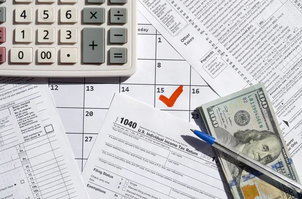 1040 Individual Income Tax Return blank with dollar bills, calculator and pen on calendar page with marked 15th April — Stock Photo, Image