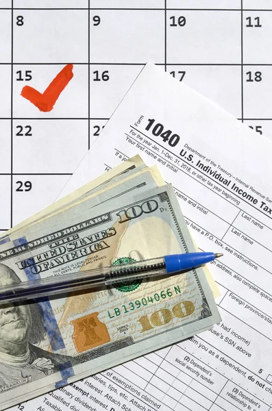 1040 Individuální přiznání k dani z příjmu s dolarovými bankovkami, kalkulačkou a perem na kalendářní stránce s označením 15. dubna — Stock fotografie