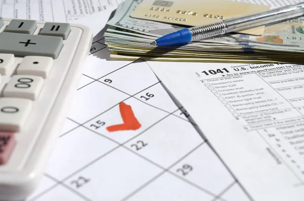 1041 Daňové přiznání k nemovitostem a svěřeneckým fondům s dolarovými bankovkami, kalkulačkou a perem na stránce kalendáře s označením 15. dubna — Stock fotografie