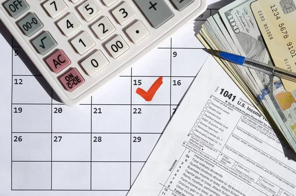 1041 Zwrot podatku dochodowego dla stanów i trustów puste z banknotów dolarowych, kalkulator i długopis na stronie kalendarza z zaznaczonym 15 kwietnia — Zdjęcie stockowe