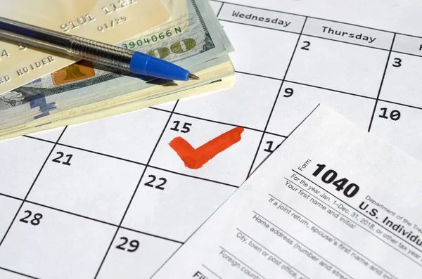 1040 Individuální přiznání k dani z příjmu prázdné s kreditní kartou na dolarových bankovkách a perem na kalendářní stránce s označením 15. dubna — Stock fotografie