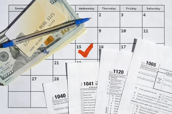 Viele wichtige Steuerformulare mit Kreditkarte auf Dollarscheinen und Stift auf Kalenderblatt mit Markierung 15. April — Stockfoto