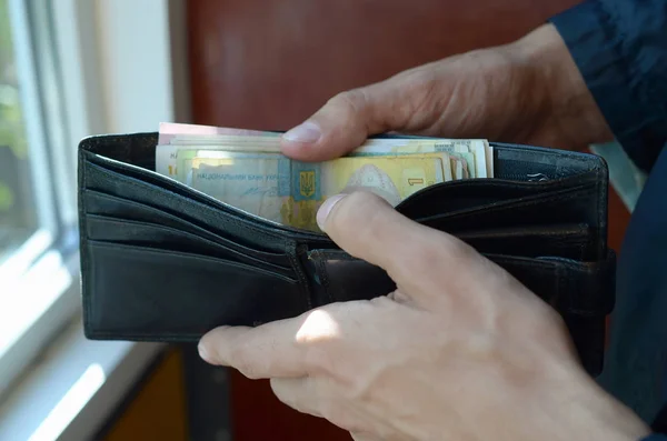 Позбавлені чоловіки відкрили гаманець або сумочку з україніанською грошовою валютою гривні. — стокове фото