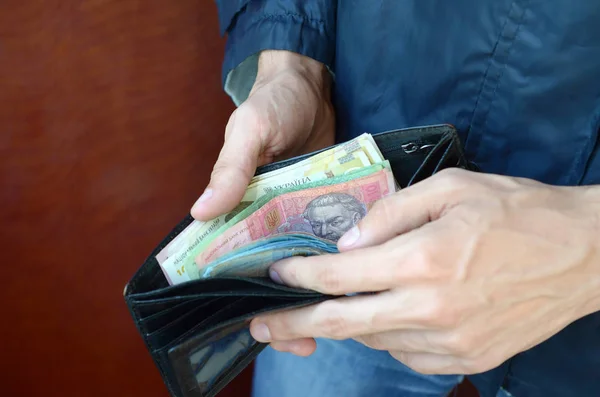 Fermer les mains masculines ouvert le portefeuille ou sac à main avec de l'argent ukrainien monnaie hryvnia — Photo