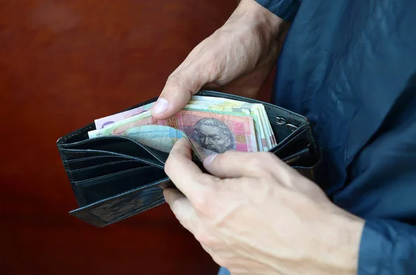 Позбавлені чоловіки відкрили гаманець або сумочку з україніанською грошовою валютою гривні. — стокове фото