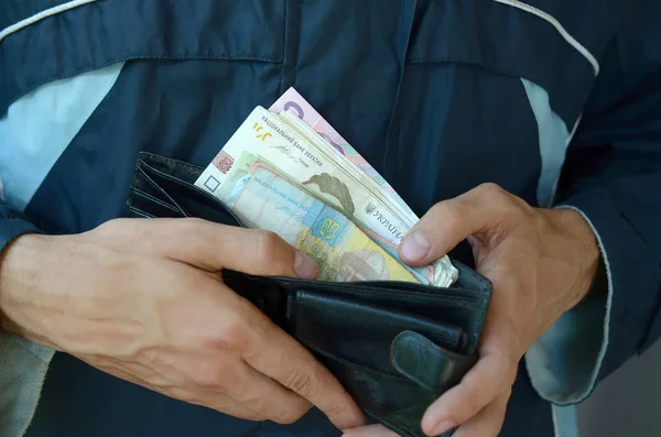 Cerca de manos masculinas abrieron la billetera o bolso con dinero ucraniano hryvnia moneda — Foto de Stock