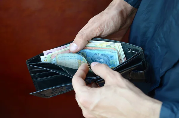 Cerca de manos masculinas abrieron la billetera o bolso con dinero ucraniano hryvnia moneda —  Fotos de Stock