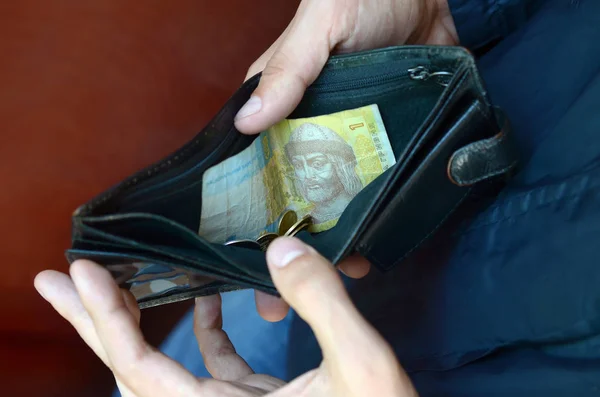 En man händer med mynt med små ukrainska räkningar och svart gammal handväska — Stockfoto