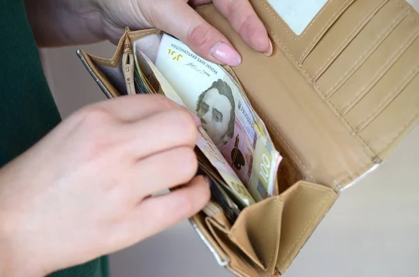 Руки женщины держат украинские гривны купюрами в небольшом денежном мешке или бумажнике — стоковое фото