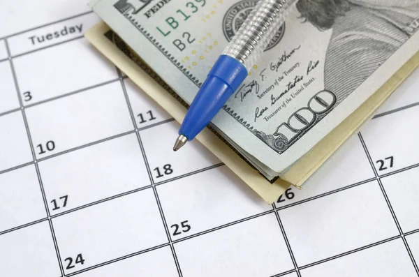 Pen and many hundred US dollar bills on calendar page close up Stock Image