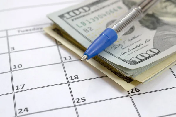 Pen and many hundred US dollar bills on calendar page close up Royalty Free Stock Photos