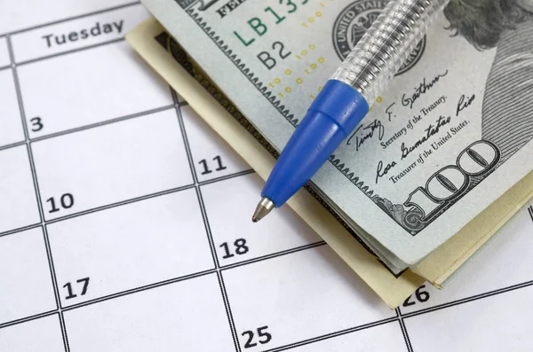 Pen and many hundred US dollar bills on calendar page close up Stock Photo