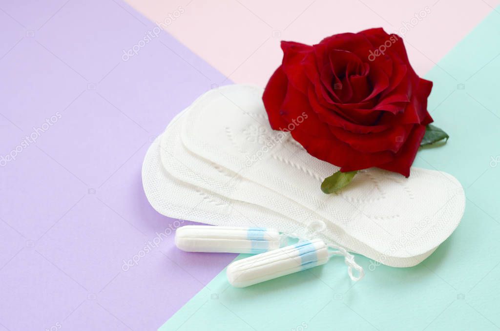 Menstrual pads and tampons with red rose flower on multicolored background