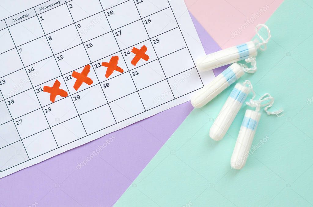 Flat lay composition with calendar and menstrual tampons on blue pink and lilac pastel background