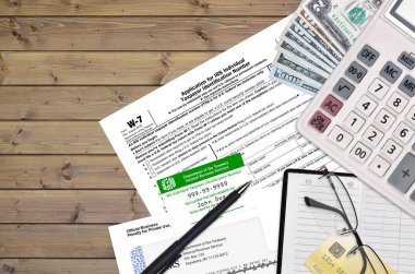 IRS form W-7 Application for IRS individual taxpayer identification number lies on flat lay office table and ready to fill. U.S. Internal revenue services paperwork concept. ITIN clipart