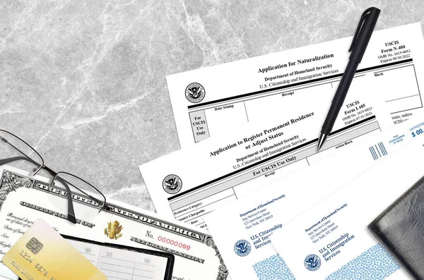 USCIS form I-485 Application to register permanent residence or adjust status and N-400 Application for naturalization with Certificate of naturalization lies on office table and ready to fill.