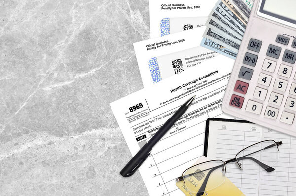 IRS form 8965 Health Coverage Exemptions lies on flat lay office table and ready to fill. U.S. Internal revenue services paperwork concept. Time to pay taxes in United States. Top view