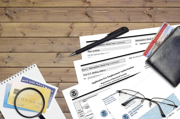 USCIS form I-765 Application for employment authorization lies on flat lay office table and ready to fill. U.S. Citizenship and Immigration services paperwork concept. Top view