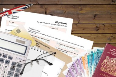 İngiliz Vergi formu sa105 UK Property from HM Gelir ve Gümrük Ofis eşyalarıyla birlikte masada yatıyor. İngiltere Birleşik Krallığında HMRC evrakları ve vergi ödeme süreci