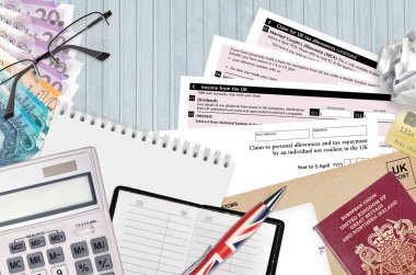 English Tax form R43 Claim to personal allowances and tax repayment by an individual not resident in the UK lies on table with office items. HMRC paperwork clipart