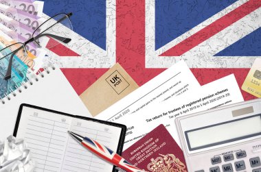 English Tax form sa970 Tax return for trustees of registered pension schemes from HM revenue and customs lies on table with office items. HMRC paperwork and tax paying process in United Kingdom clipart