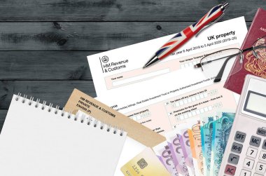 İngiliz Vergi formu sa105 UK Property from HM Gelir ve Gümrük Ofis eşyalarıyla birlikte masada yatıyor. İngiltere Birleşik Krallığında HMRC evrakları ve vergi ödeme süreci