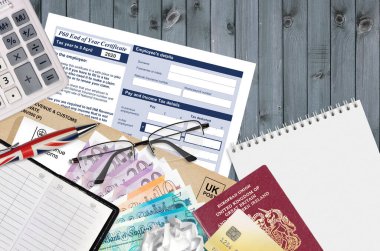 HM gelir ve gümrük sertifikası ile İngiliz Vergi formu P60 yıl sonu sertifikası ofis eşyalarıyla birlikte masadadır. İngiltere Birleşik Krallığında HMRC evrakları ve vergi ödeme süreci