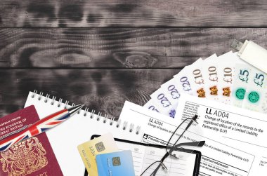 LLAD04 İngilizce formunda, şirket evi servisinin sınırlı sorumluluk ortaklığı LLP 'sinin tescilli ofisine yapılan kayıtların konumu ofis eşyalarıyla birlikte masada yatıyor. CH evrak süreci