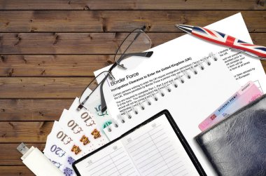Sınır Gücü hizmetlerinden İngiltere 'ye giriş izni almak için İngiliz Göçmen Bürosu formu ofis eşyalarıyla birlikte masada yatıyor. İngiltere sınır gücü evrak işlemleri