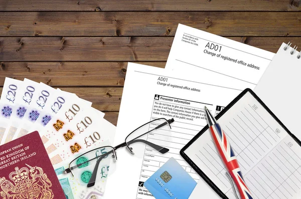 Şirket Hizmetleri 'nden kayıtlı ofis adresi değişikliğinin İngilizce formu AD01 ofis eşyalarıyla birlikte masadadır. Birleşik Krallık 'ta CH iş ve evrak süreci