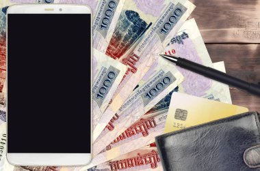 1000 Kamboçyalı isyan faturası ve çantalı ve kredi kartlı akıllı telefon. E-ödemeler ya da e-ticaret konsepti. Taşınabilir aygıt kullanımı ile çevrimiçi alışveriş ve iş