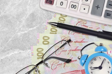 100 Ukrayna hrivniası fatura ve kalem ve gözlüklü hesap makinesi. İş kredisi ya da vergi ödeme sezonu kavramı. Mali planlama ve vergi ödeme zamanı