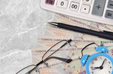 5 Türk lirası, gözlüklü ve kalemli hesap makinesi. İş kredisi ya da vergi ödeme sezonu kavramı. Mali planlama ve vergi ödeme zamanı